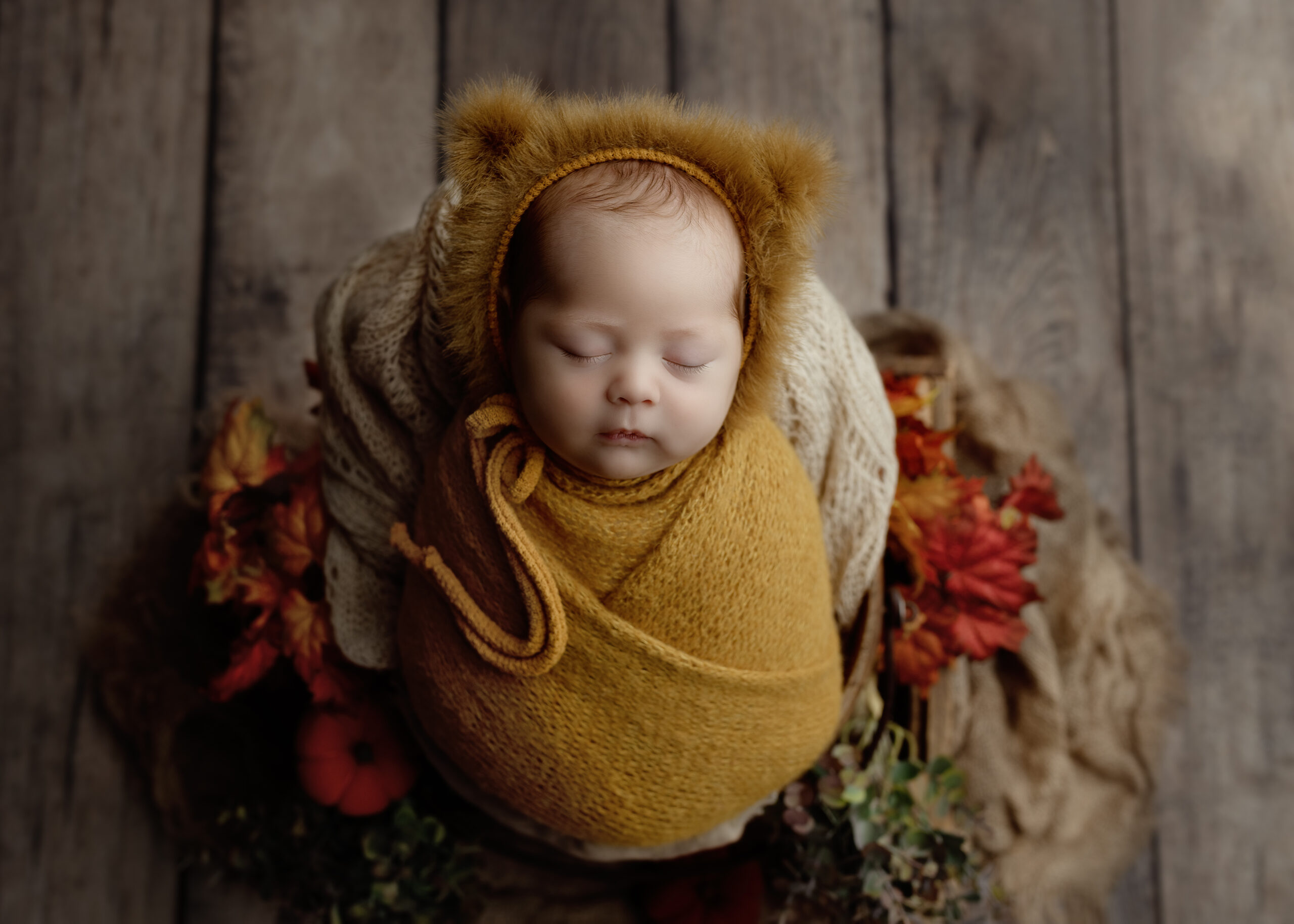 A professional newborn photographer in Ontario capturing a peaceful newborn baby wrapped in soft, neutral-toned blankets during a luxury studio session.